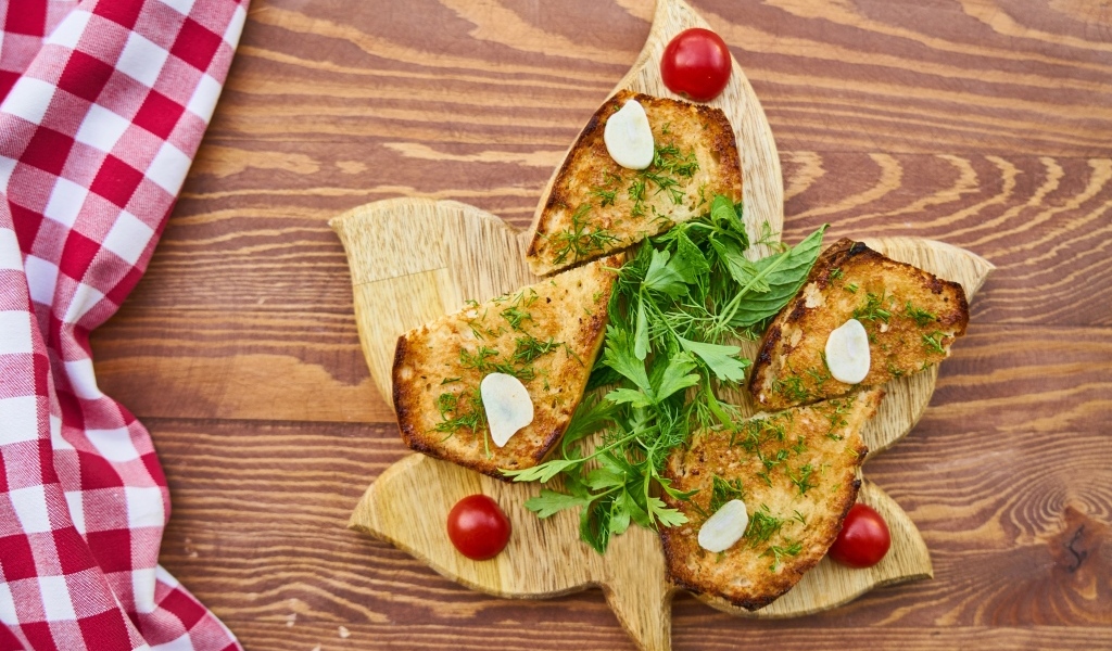 Жареный хлеб на доске с зеленью и помидорами