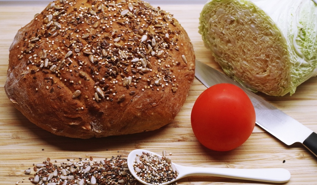 Буханка хлеба на столе с капустой и помидором