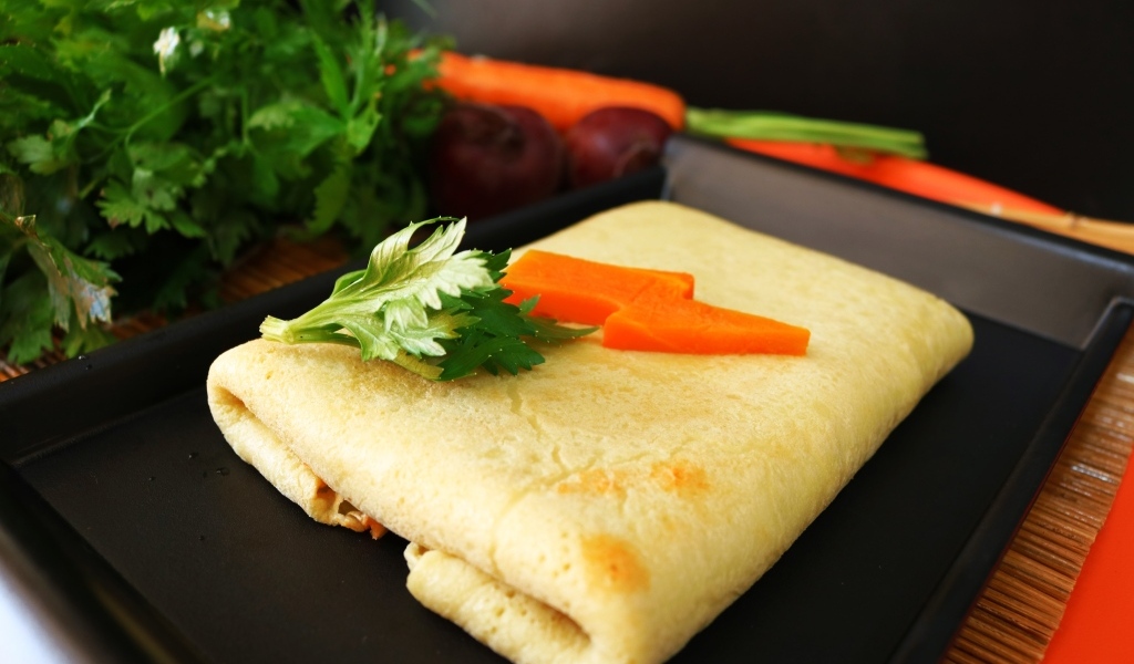 Блинчик на тарелке с морковью и веточками петрушки