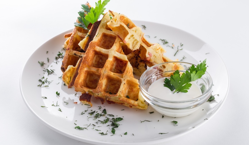 Вафли с соусом и зеленью на тарелке