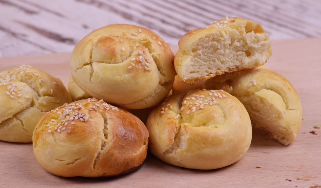 Аппетитные сладкие булочки с кунжутом на столе