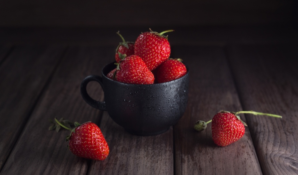 Черная чашка с красными ягодами клубники