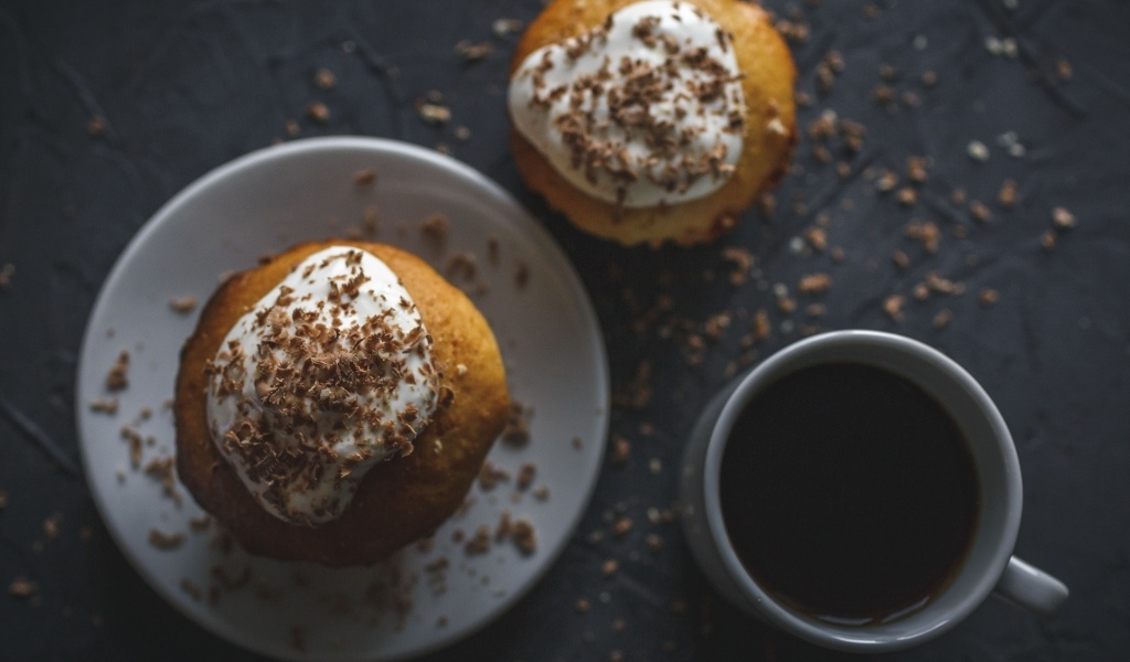 Пирожное в тертым шоколадом на столе с чашкой кофе