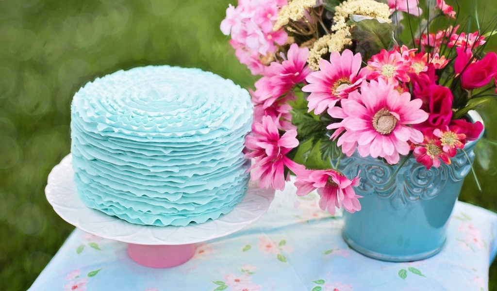 Торт с голубым кремом на столе с цветами