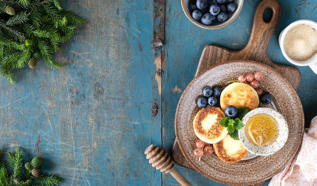 Сырники с ягодами черники на тарелке с медом