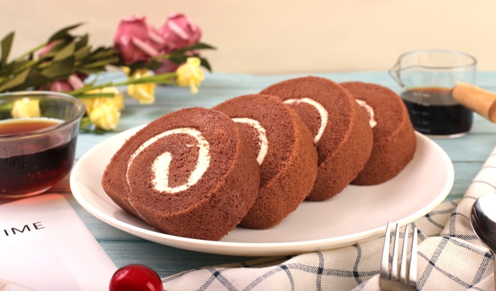 Шоколадный бисквитный рулет с кремом на тарелке