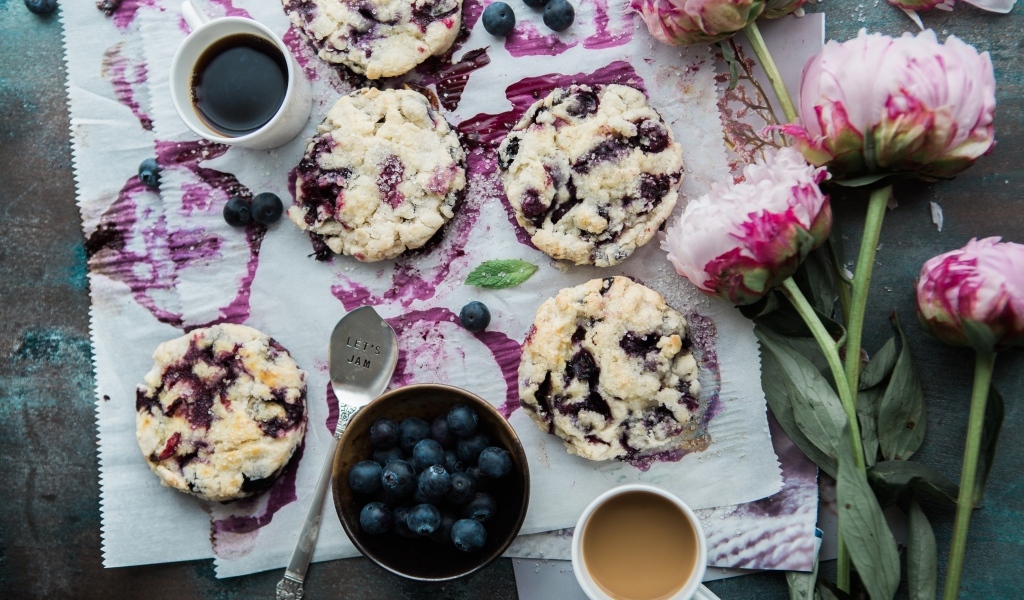 Печенье с ягодами черники на столе с цветами и кофе