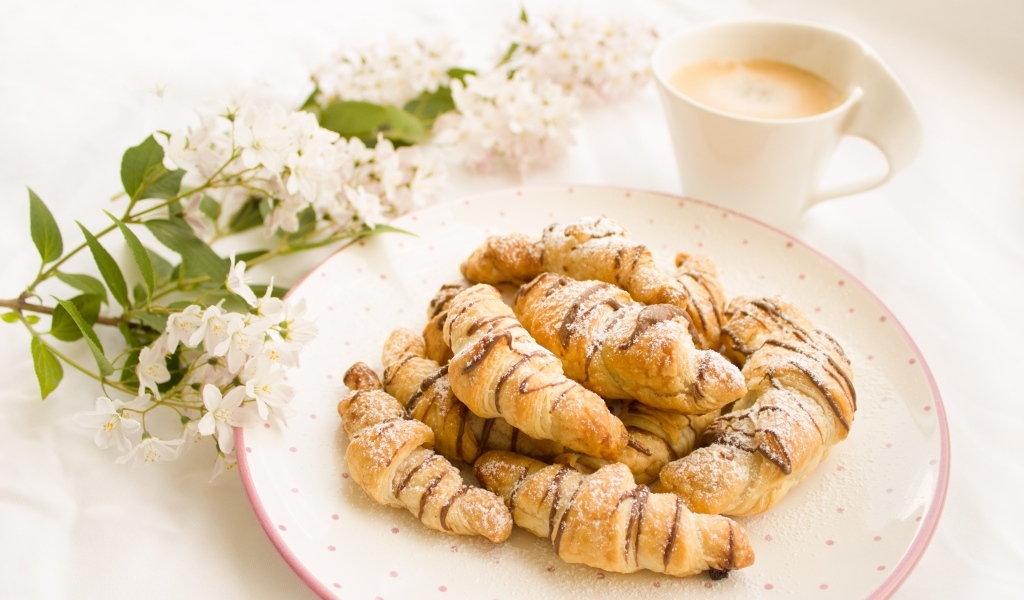 Круассаны на столе с кофе и цветами