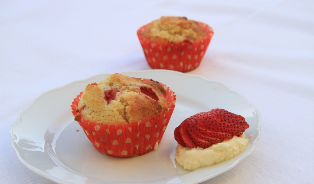 Кекс на большой белой  тарелке с кремом и клубникой