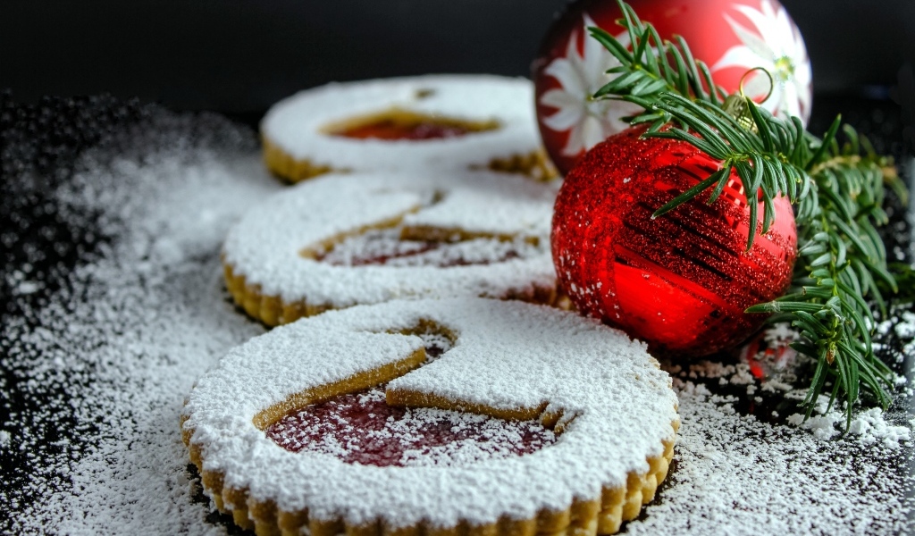 Вкусное сладкое печенье в сахарной пудре на столе с елочными игрушками