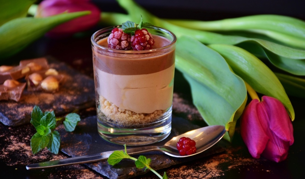 Десерт в стакане на столе с тюльпаном