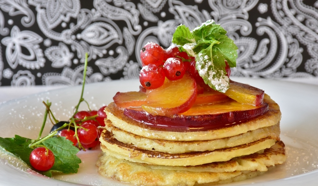 Оладьи на тарелке с ягодами смородины  и сливы