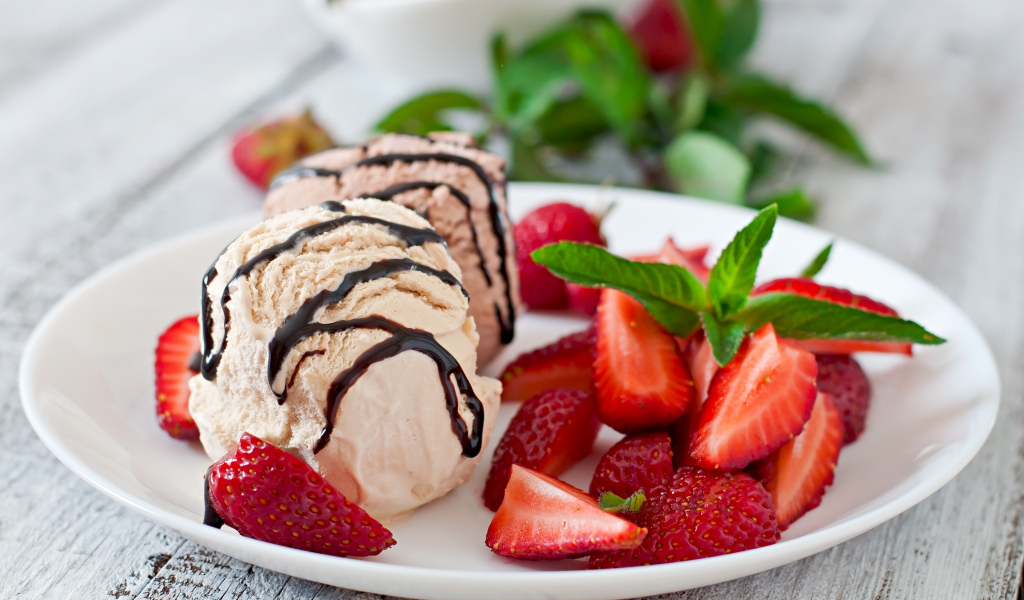 Шарики мороженого на тарелке с кусочками клубники