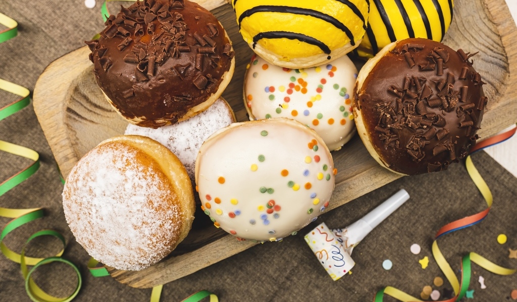 Много сладких пончиков в глазури на столе