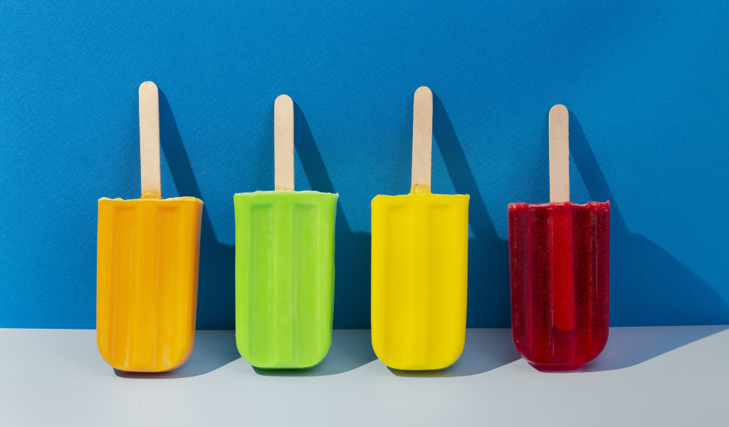 Разноцветное фруктовое мороженое на фоне голубой стены