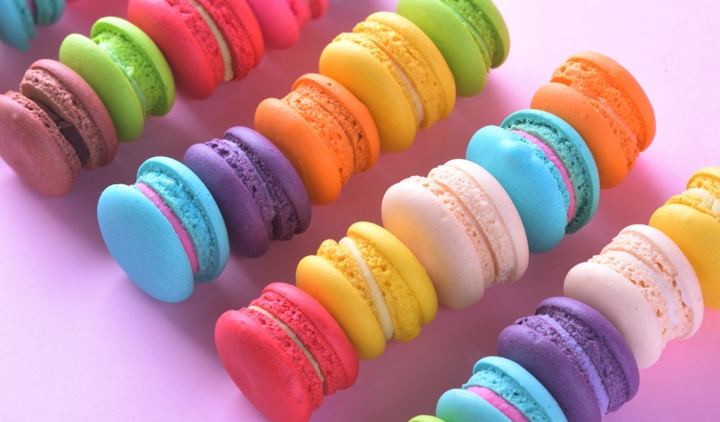 Разноцветный десерт макарун на розовом столе
