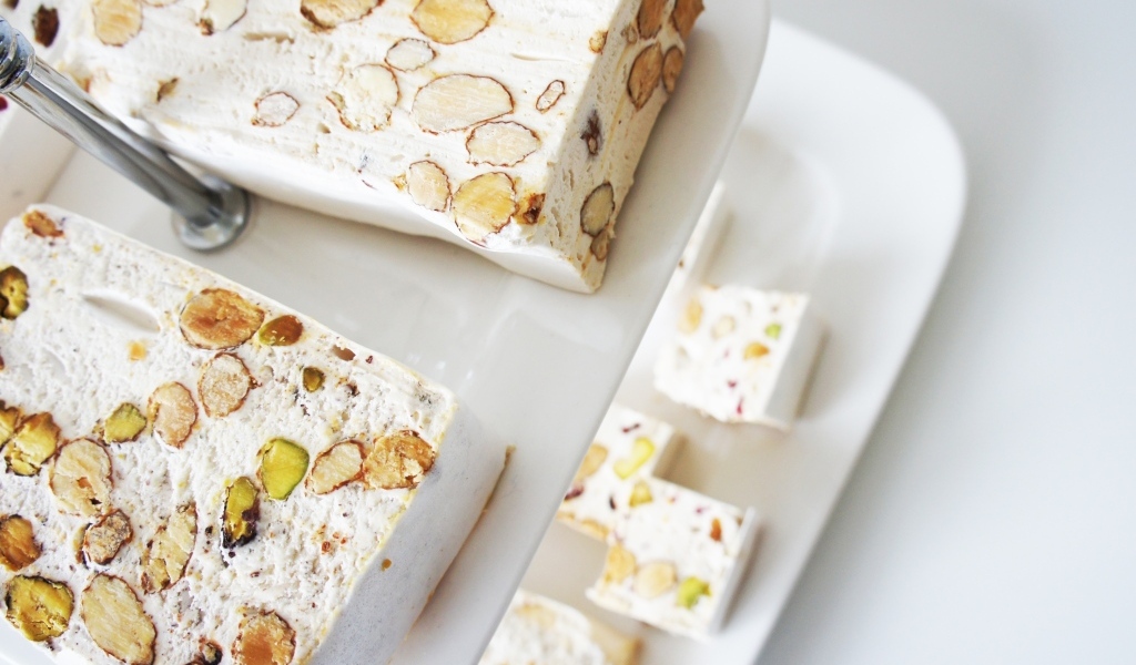 Нуга с орехами на белой тарелке