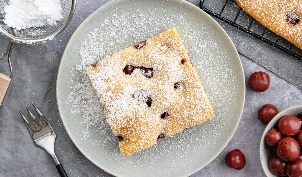 Кусок вишневого пирога на тарелке с сахарной пудрой