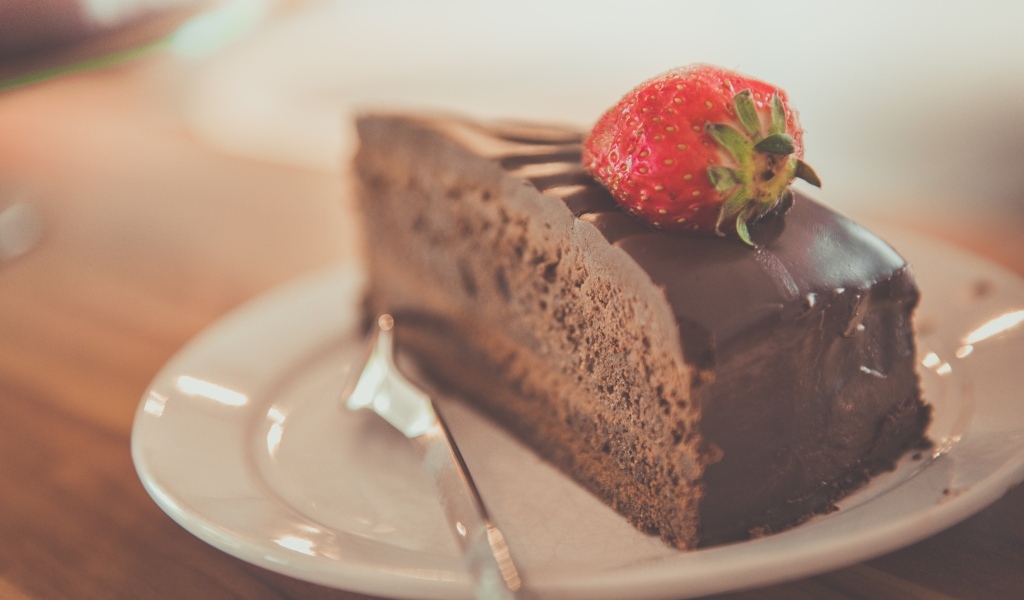 Кусок шоколадного торта с клубникой на тарелке