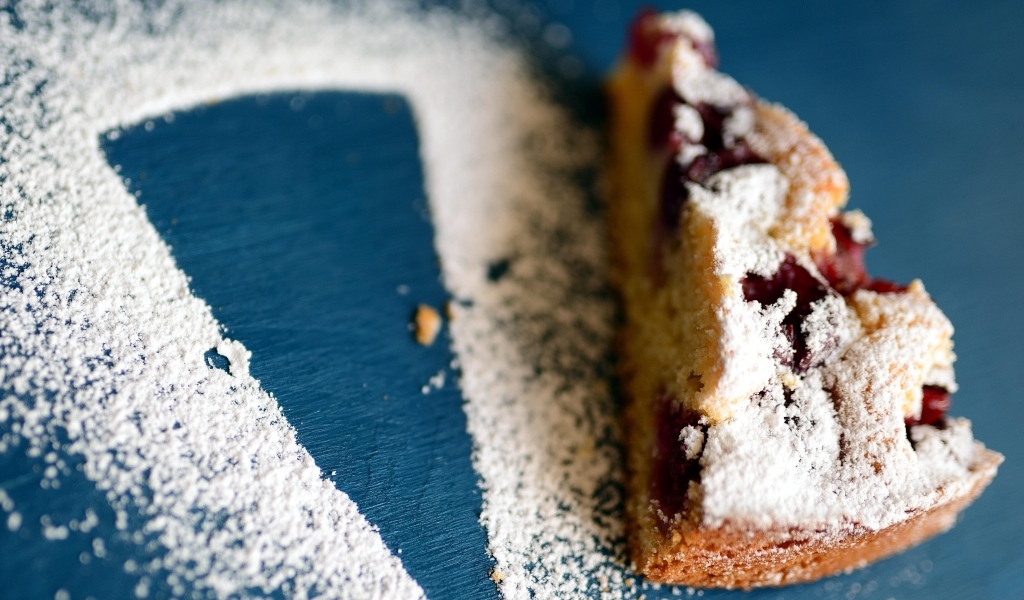 Кусок пирога с ягодами на столе с сахарной пудрой