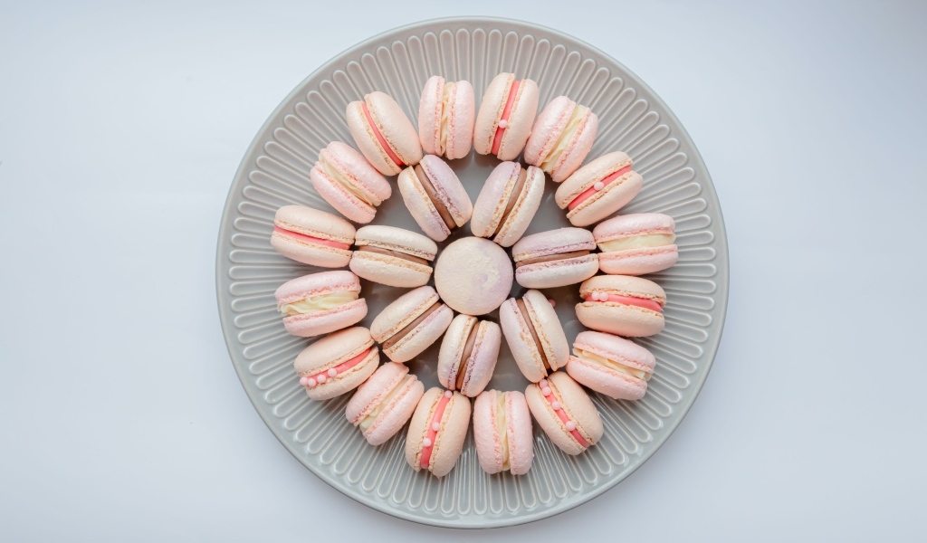 Розовый десерт макарон на большой тарелке