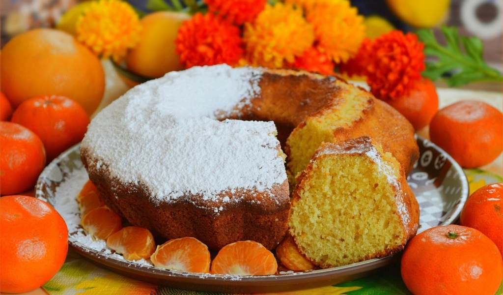 Сладкий пирог на столе с мандаринами и апельсинами