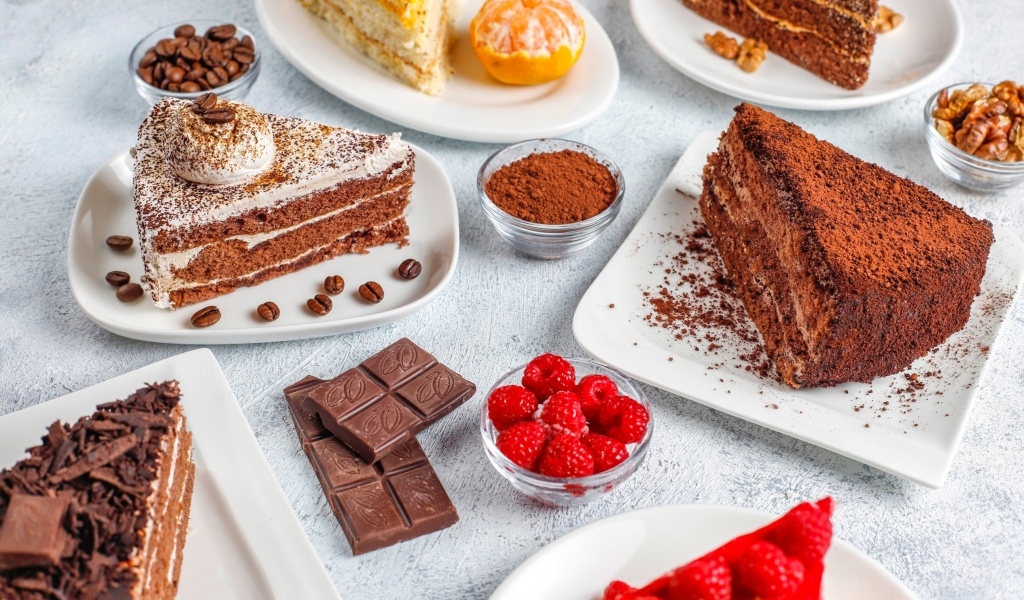 Сладкие куски торта на столе с шоколадом и ягодами