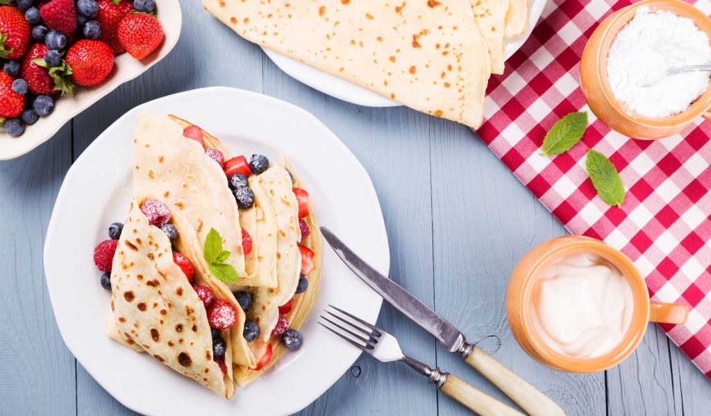 Сладкие тонкие блинчики с ягодами на тарелке