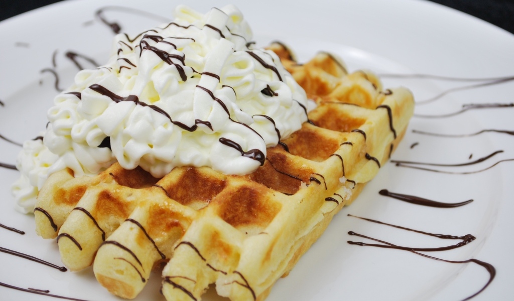 Сладкая вафля со сливками на белой тарелке