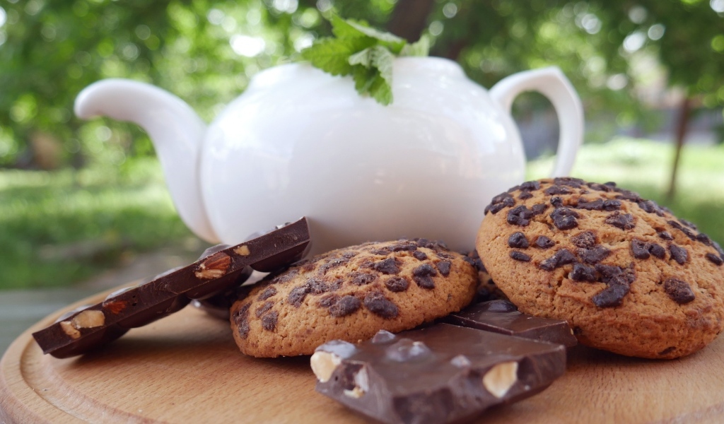 Чайник на столе с печеньем и шоколадом