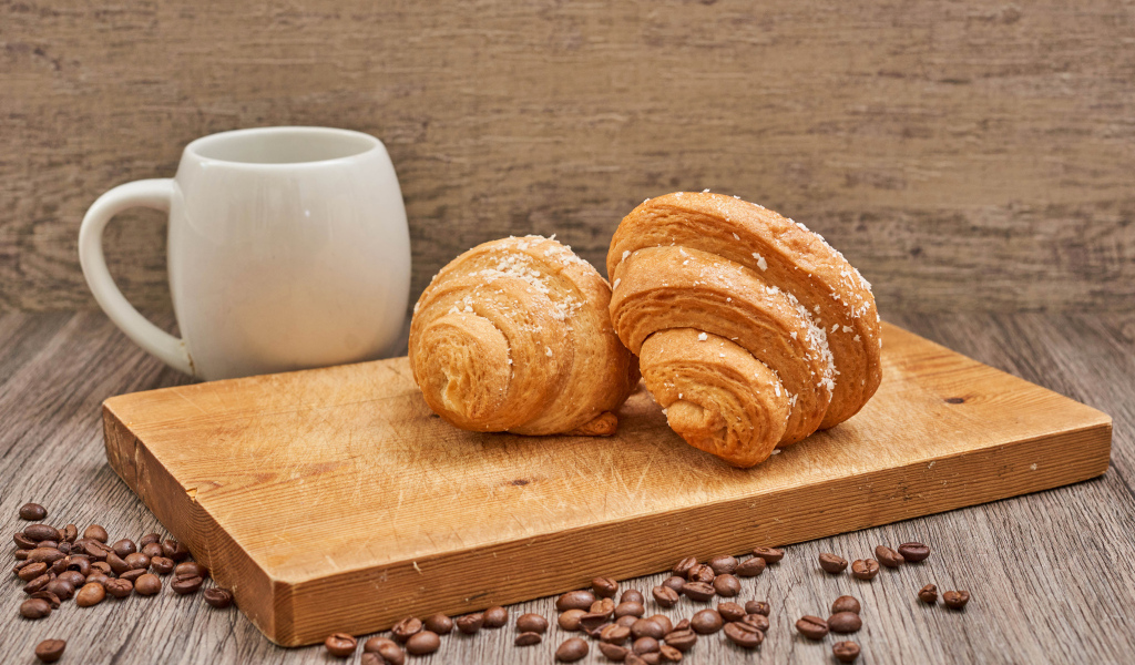 Два круассана на доске с кофейными зернами