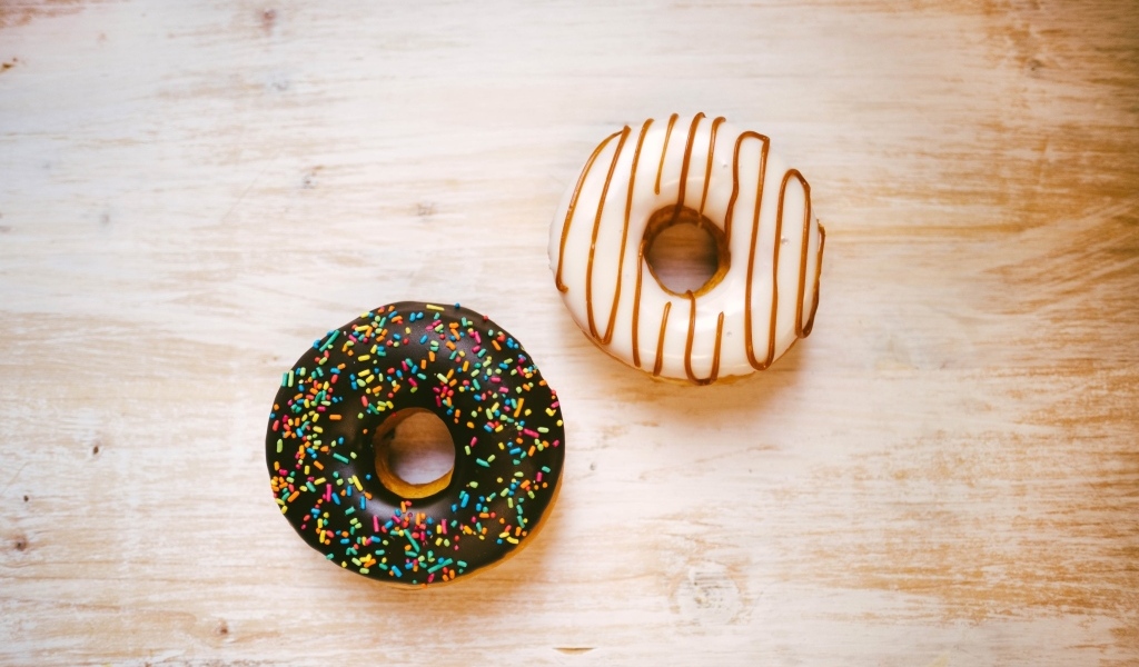 Два пончика в глазури на деревянном столе