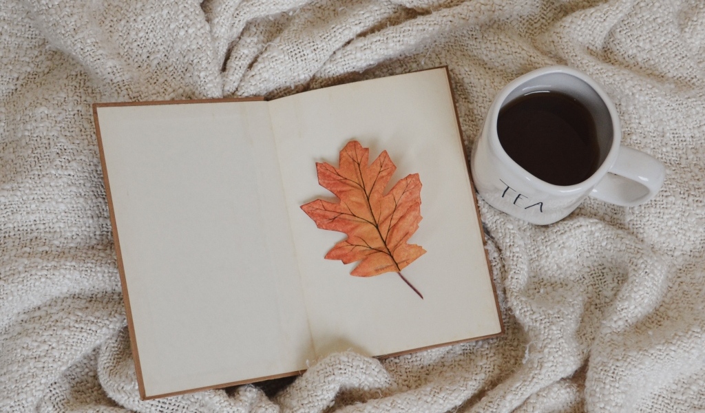 Книга, желтый лист и чашка кофе с пледом