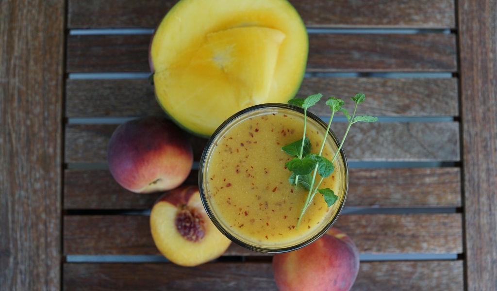 Коктейль с веточкой мяты на столе с фруктами