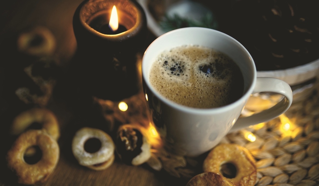 Чашка кофе на столе со свечой и печеньем
