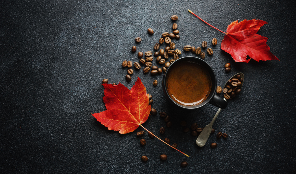 Чашка кофе на столе с зернами и желтыми листьями
