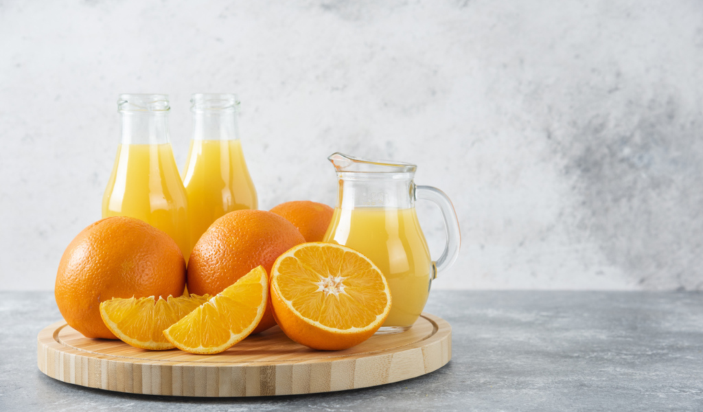 Свежевыжатый сок на столе с апельсинами