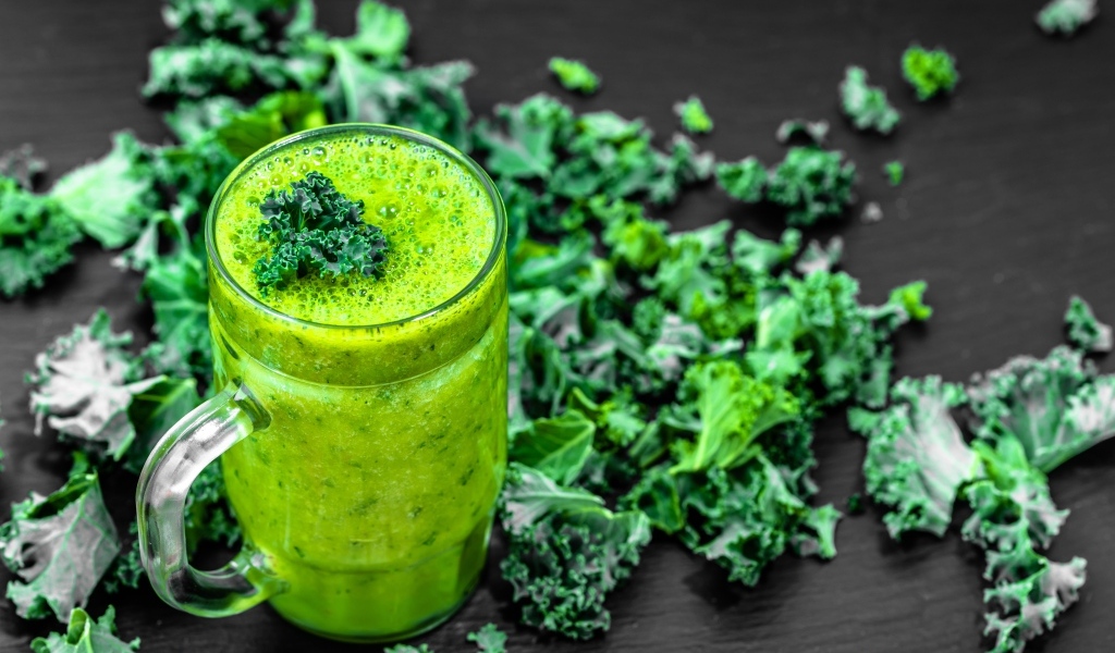 Бокал с зеленым смузи с листьями