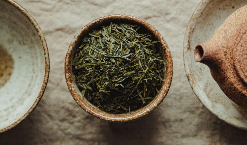 Зеленый чай в пиале на столе с чайником