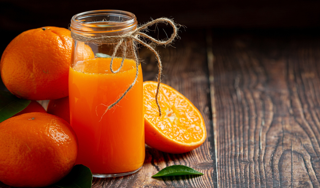 Банка свежего сока на столе с мандаринами