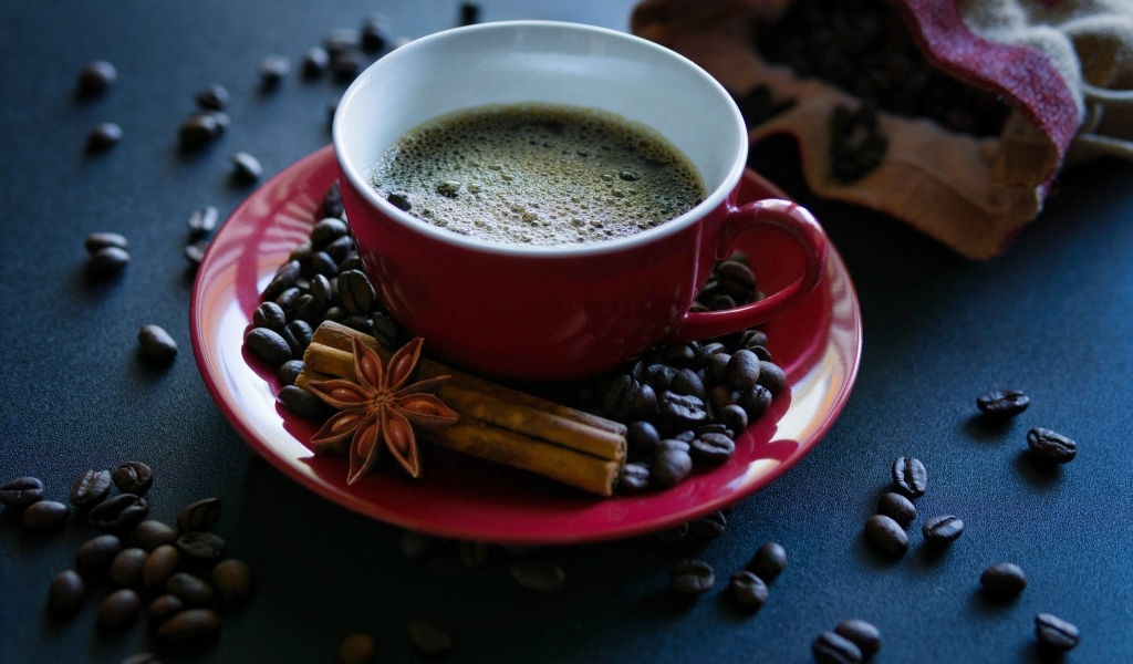 Красная чашка кофе на столе со специями и зернами