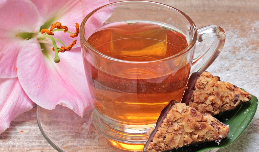 Чай на столе с розовой лилией и конфетами