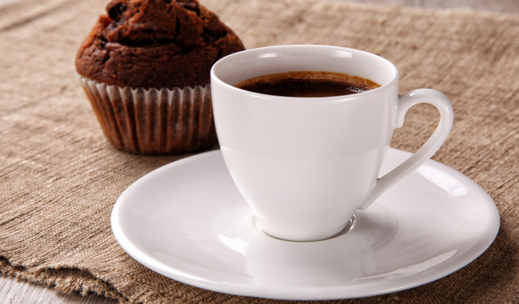 Белая чашка кофе на столе с кексом