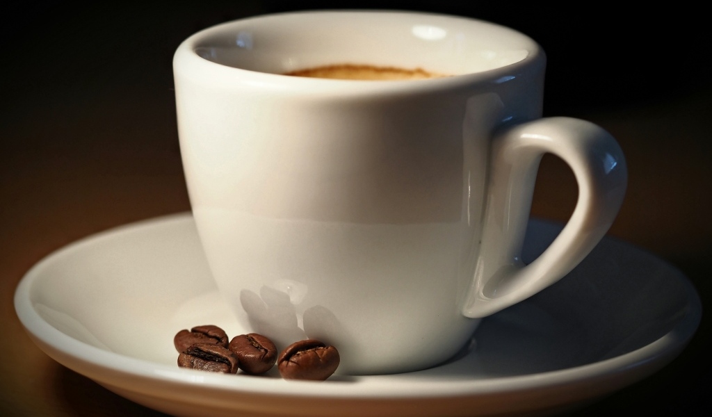 Белая чашка кофе с зернами крупным планом