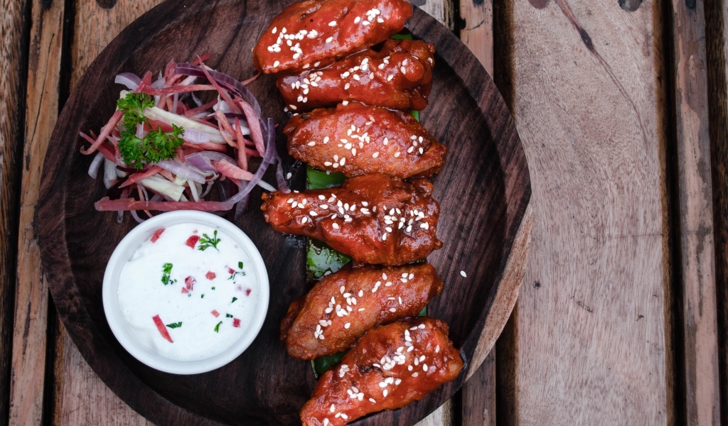 Запеченные куриные крылышки с соусом на тарелке