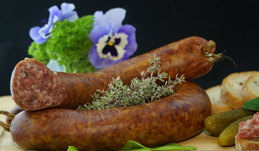 Свежая домашняя колбаса на столе с цветами