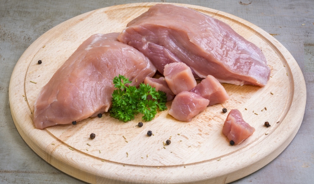 Свежая свинина на разделочной доске с петрушкой