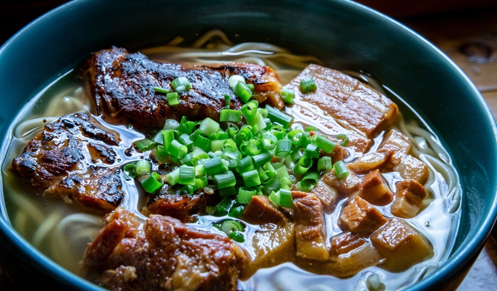 Лапша с мясом и зеленым луком в тарелке