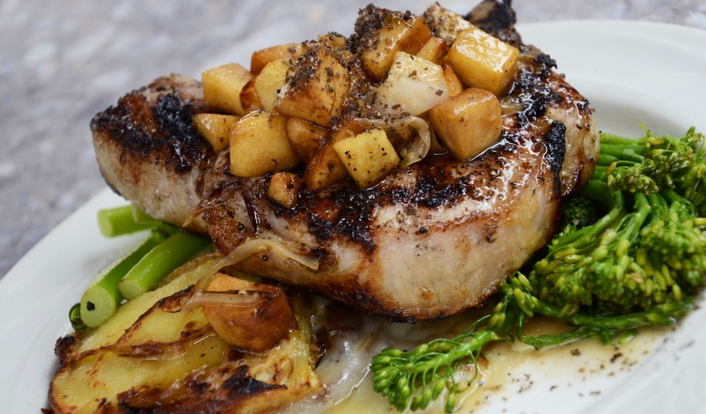 Кусок запеченного мяса на тарелке с овощами