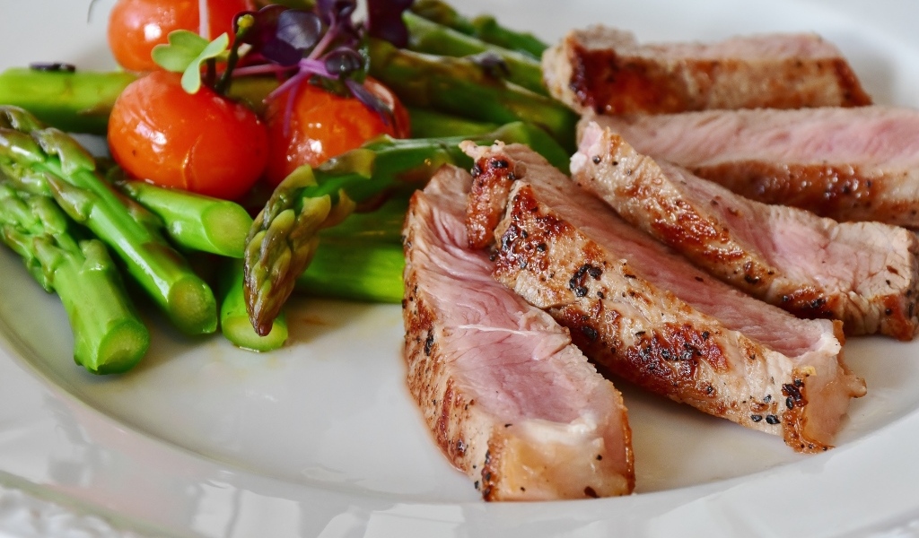 Куски аппетитного мяса на тарелке со спаржей